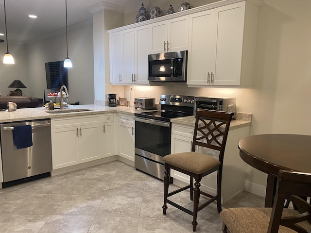 kitchen with sink, white cabinets, appliances with stainless steel finishes, and hanging light fixtures