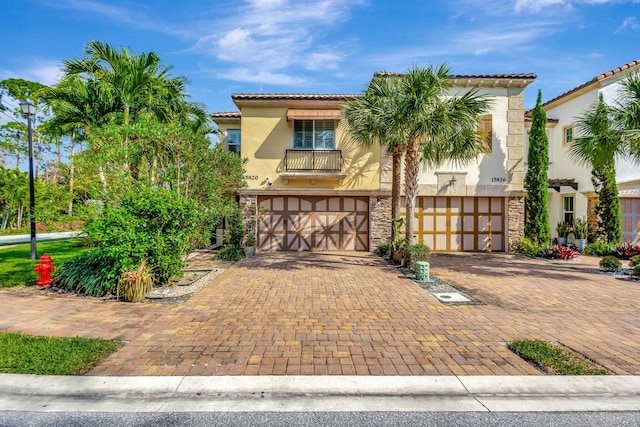 mediterranean / spanish home featuring a garage and a balcony