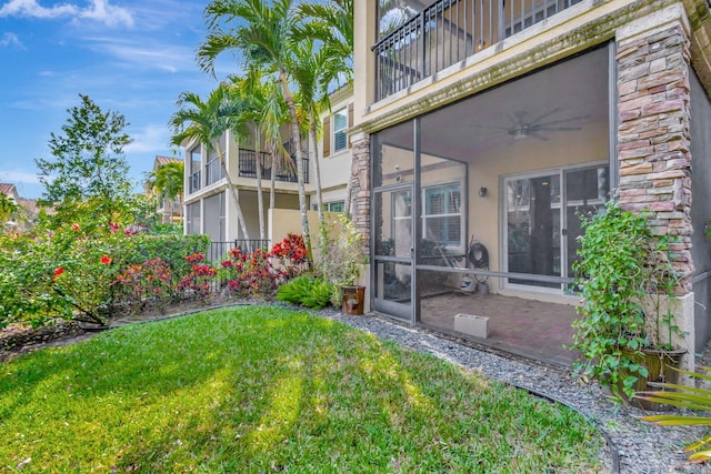 view of yard with ceiling fan, a balcony, and a sunroom