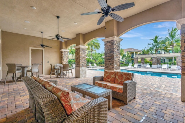 view of patio featuring an outdoor living space, an outdoor bar, a community pool, and ceiling fan