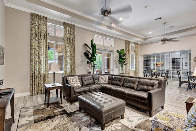 living room featuring crown molding, light hardwood / wood-style flooring, ceiling fan, and a tray ceiling