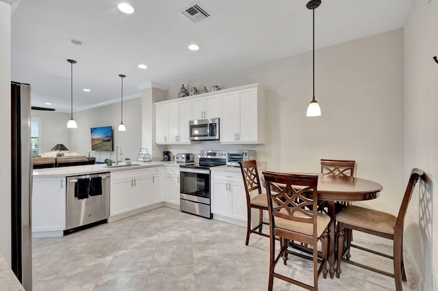 kitchen with hanging light fixtures, stainless steel appliances, sink, and white cabinets