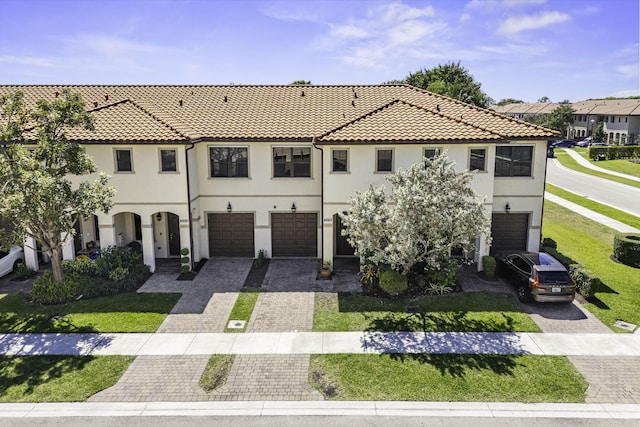 view of front facade featuring stucco siding, driveway, an attached garage, and a front lawn