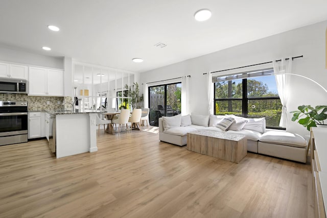 living area with recessed lighting, visible vents, and light wood finished floors