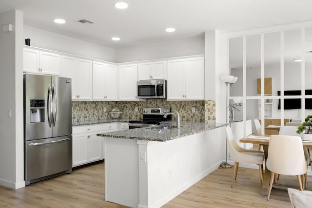 kitchen featuring stone counters, backsplash, white cabinetry, and stainless steel appliances