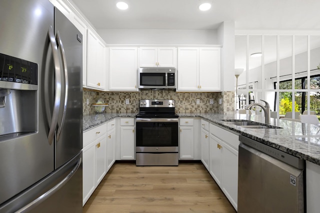 kitchen featuring a sink, stainless steel appliances, tasteful backsplash, and white cabinetry