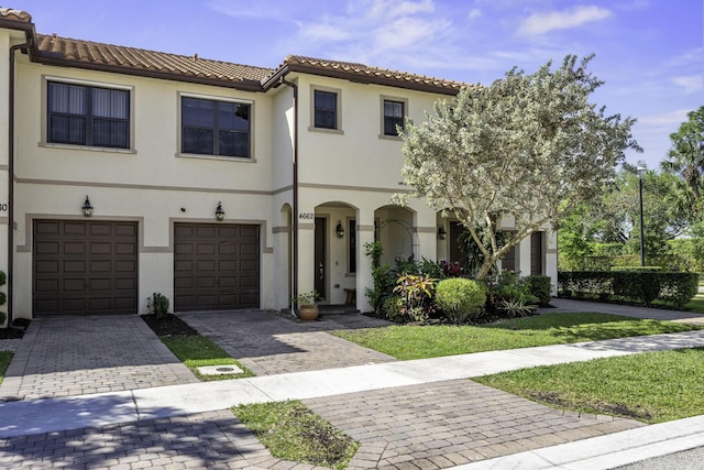 view of front of home with a tiled roof, decorative driveway, a garage, and stucco siding