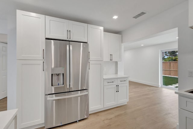 kitchen with stainless steel refrigerator with ice dispenser, white cabinets, and light hardwood / wood-style flooring