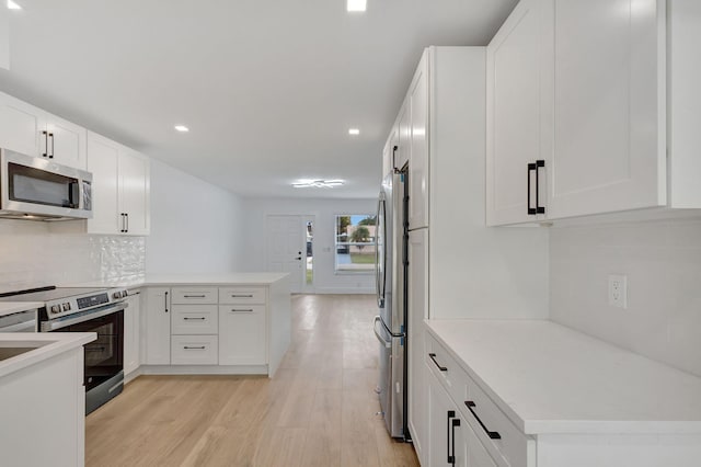 kitchen featuring appliances with stainless steel finishes, white cabinetry, decorative backsplash, light hardwood / wood-style floors, and kitchen peninsula