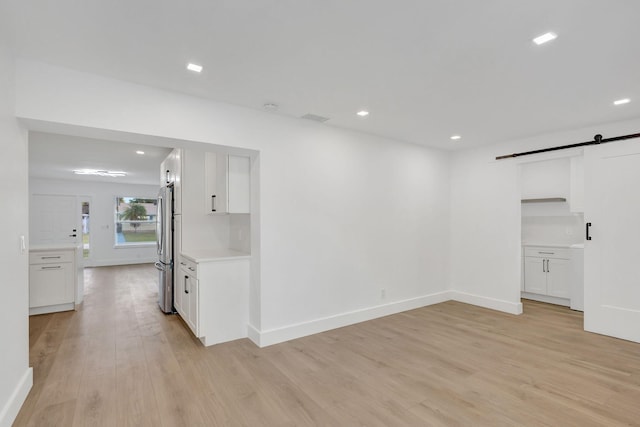 unfurnished room featuring a barn door and light hardwood / wood-style flooring