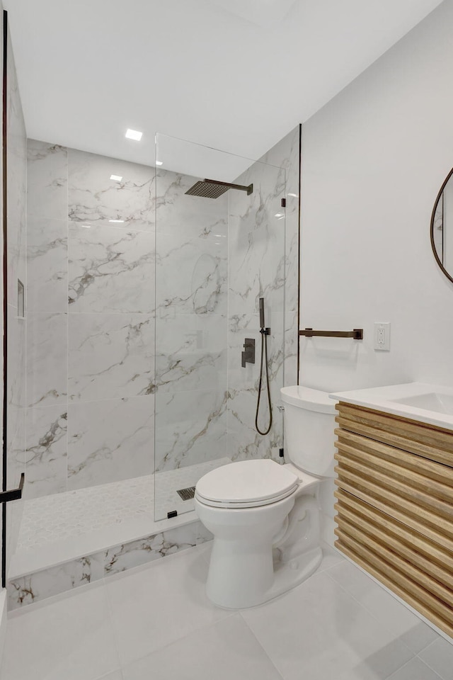 bathroom featuring vanity, a tile shower, and toilet