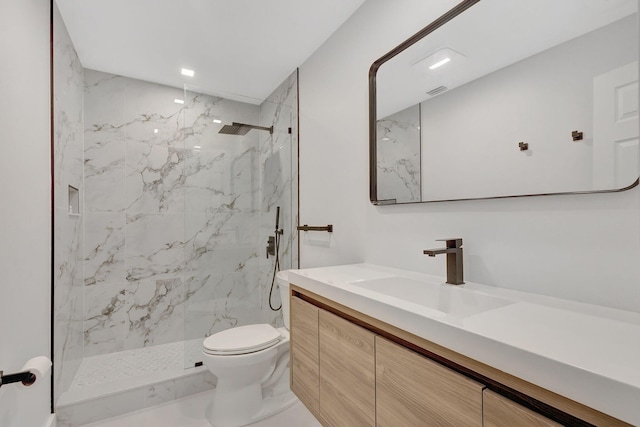 bathroom featuring vanity, a tile shower, and toilet