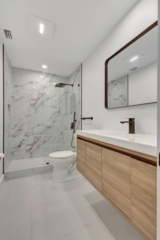 bathroom featuring tiled shower, vanity, toilet, and tile patterned floors