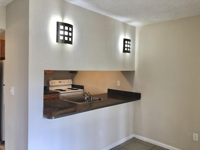 kitchen with electric stove, a textured ceiling, tile patterned floors, and sink