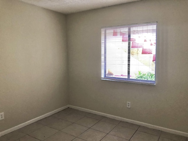 tiled empty room with a textured ceiling