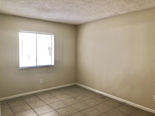 tiled empty room featuring a textured ceiling