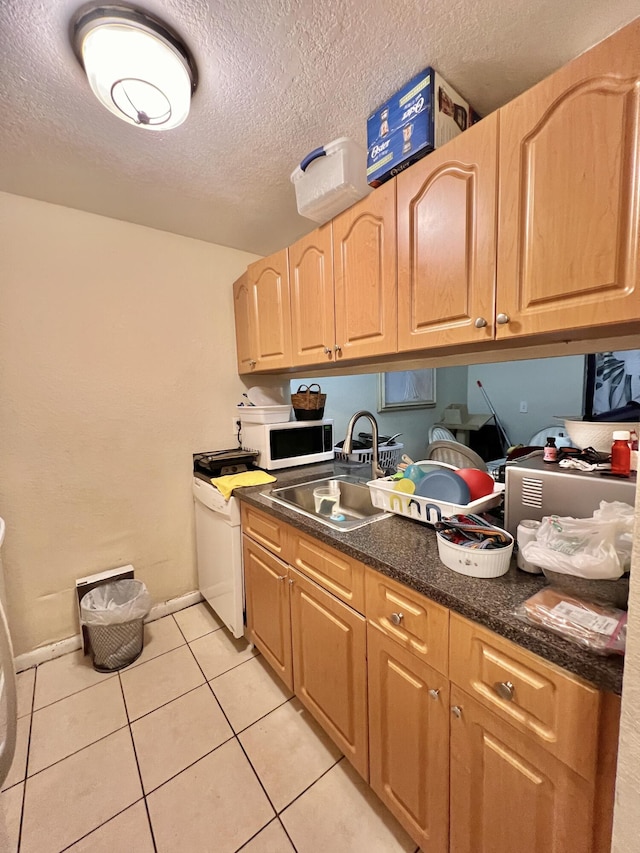 kitchen with light brown cabinetry, sink, a textured ceiling, and light tile patterned floors