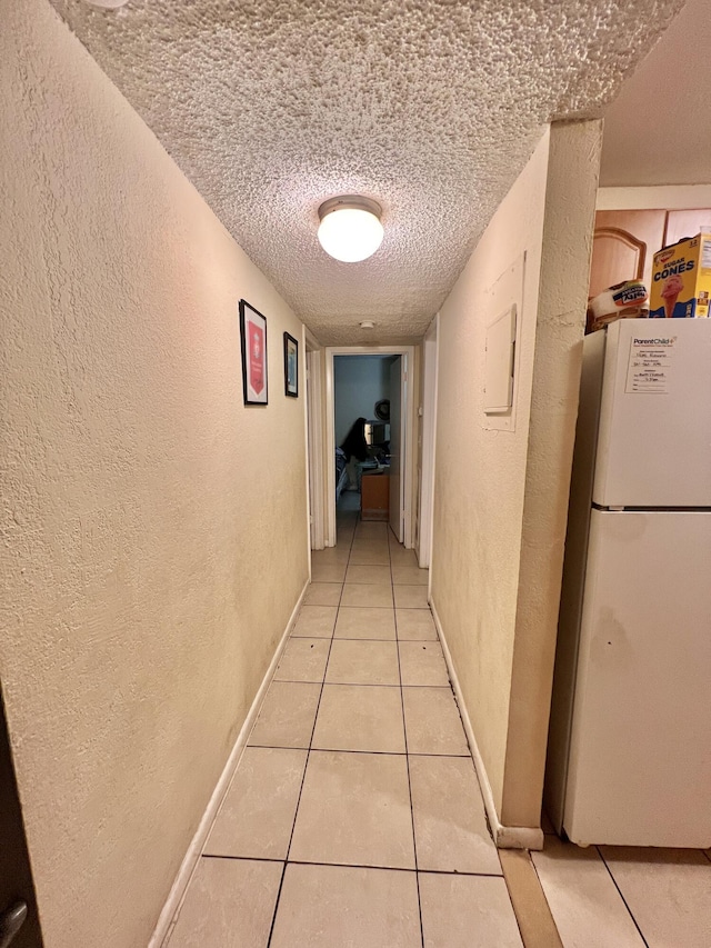 hall featuring a textured ceiling and light tile patterned flooring