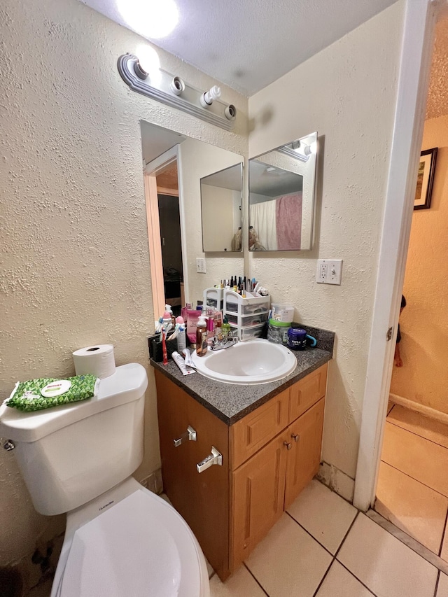 bathroom with toilet, tile patterned flooring, and vanity