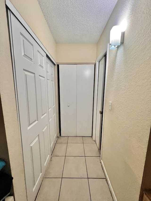 hall featuring a textured ceiling and light tile patterned floors