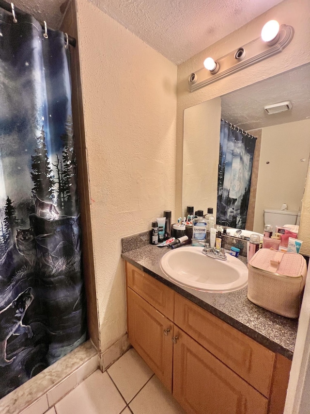 bathroom with toilet, vanity, tile patterned flooring, and a textured ceiling