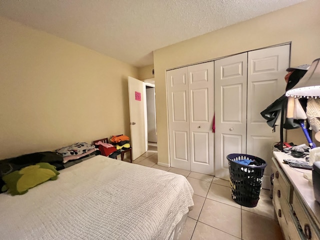 bedroom with a textured ceiling, a closet, and light tile patterned flooring