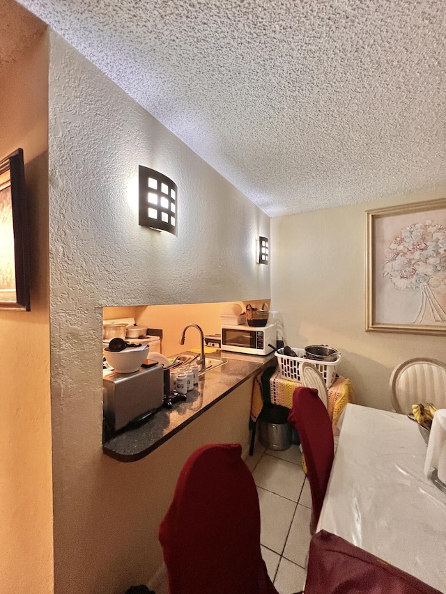 interior space featuring a textured ceiling, tile patterned floors, and sink