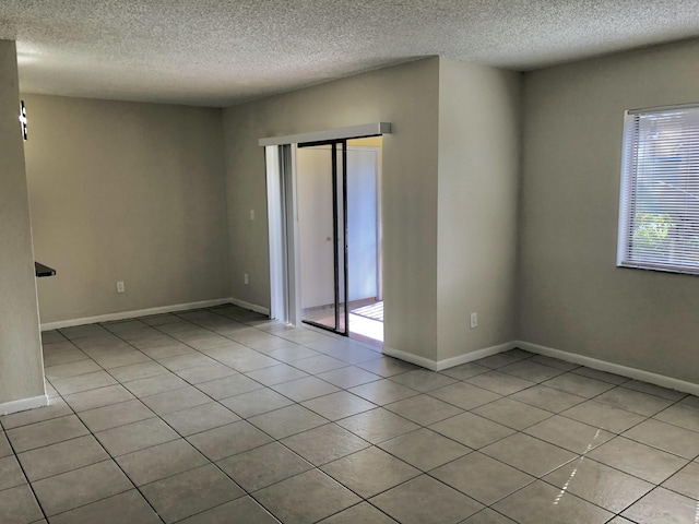 tiled empty room with a healthy amount of sunlight and a textured ceiling