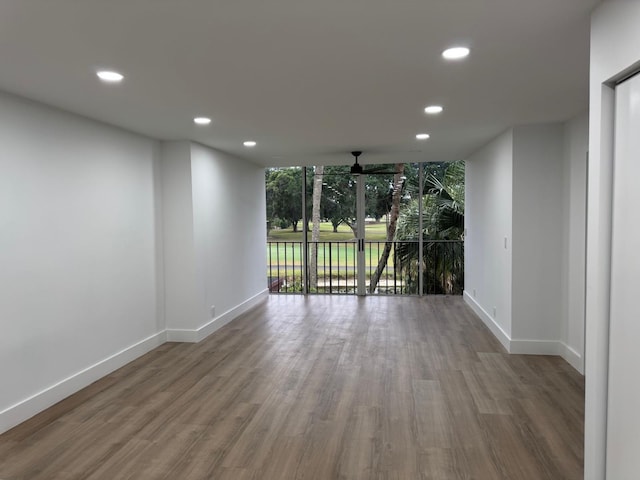 unfurnished room with ceiling fan, wood-type flooring, and a wall of windows