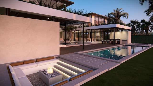 pool at dusk featuring an outdoor fire pit, a hot tub, and a patio area