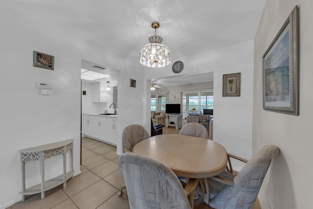 dining space with ceiling fan with notable chandelier, sink, and light tile patterned floors