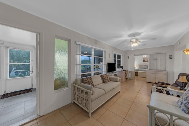 living room featuring light tile patterned flooring, ornamental molding, and ceiling fan