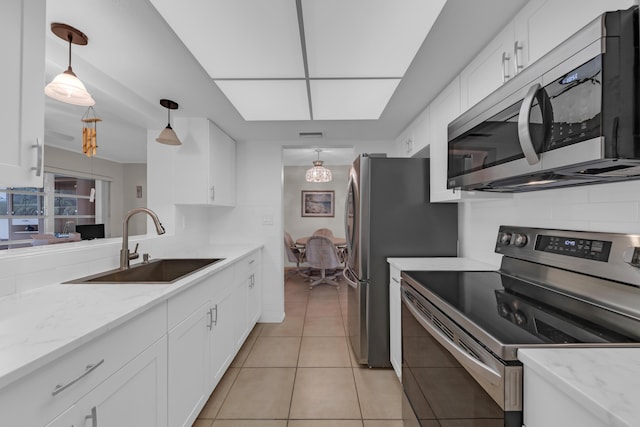 kitchen featuring stainless steel appliances, decorative light fixtures, sink, and white cabinets