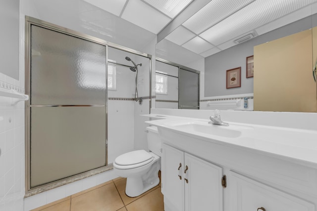 bathroom with tile patterned flooring, vanity, a shower with door, and toilet