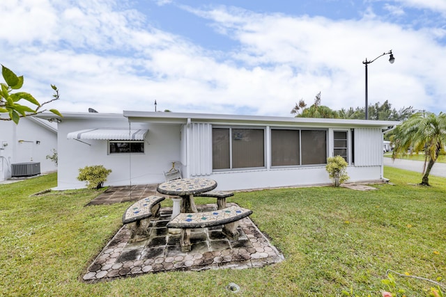 back of house with central AC, a patio, and a lawn