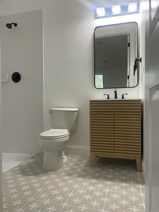 bathroom with vanity, toilet, and a tile shower