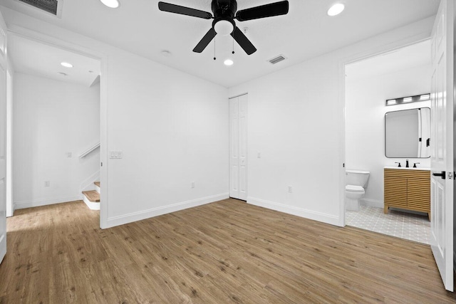 unfurnished bedroom with ensuite bathroom, hardwood / wood-style flooring, a closet, sink, and ceiling fan