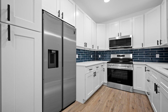 kitchen featuring white cabinets, tasteful backsplash, and stainless steel appliances