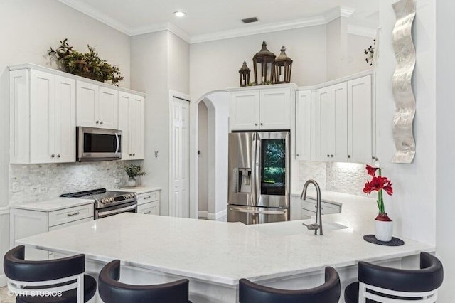 kitchen featuring tasteful backsplash, stainless steel appliances, a breakfast bar, and white cabinets