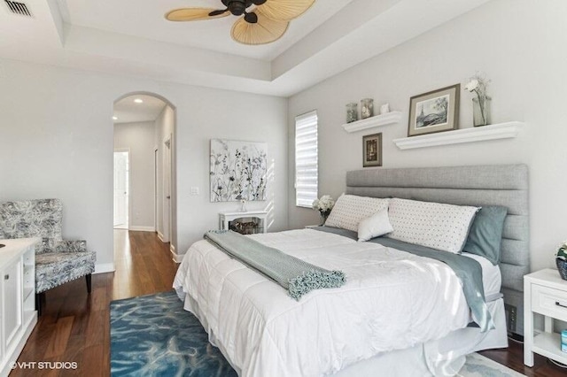 bedroom with ceiling fan, dark hardwood / wood-style flooring, and a raised ceiling