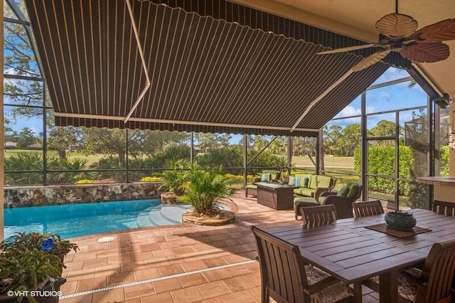 view of pool with an outdoor living space, a patio area, ceiling fan, and glass enclosure