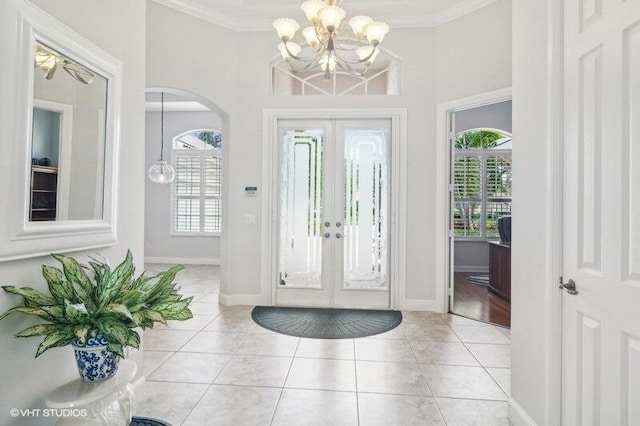 tiled foyer featuring a wealth of natural light, ornamental molding, and french doors