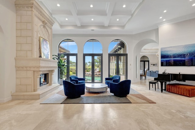 living room with coffered ceiling, ornamental molding, a towering ceiling, and a high end fireplace