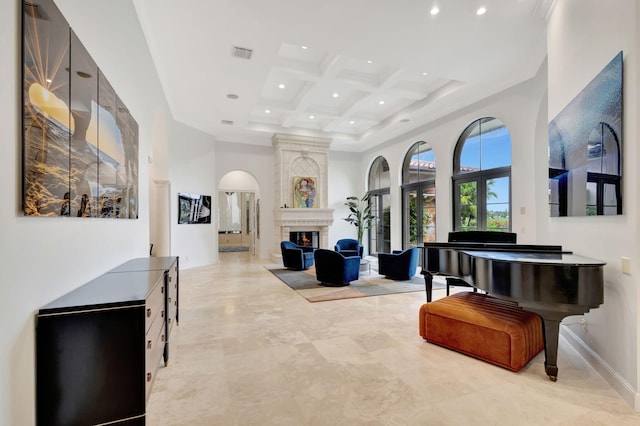 interior space featuring beamed ceiling, a towering ceiling, coffered ceiling, and a fireplace