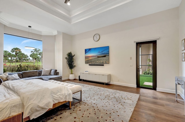 bedroom with crown molding, light hardwood / wood-style flooring, and a raised ceiling