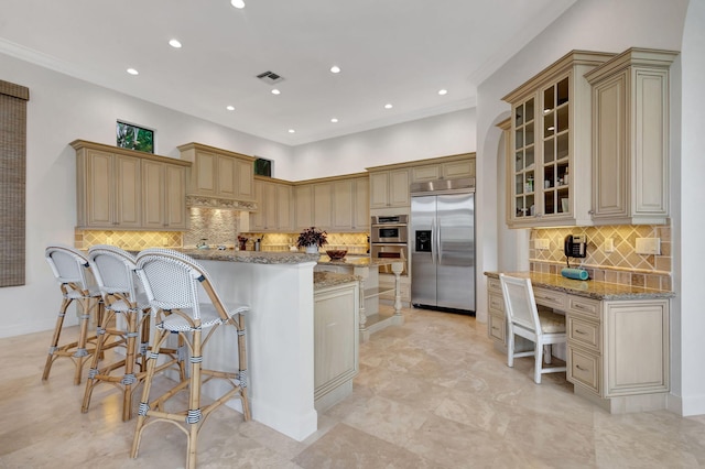 kitchen featuring light stone counters, a center island, a kitchen breakfast bar, stainless steel appliances, and decorative backsplash