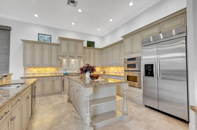 kitchen with stainless steel appliances, a center island, sink, and light stone counters