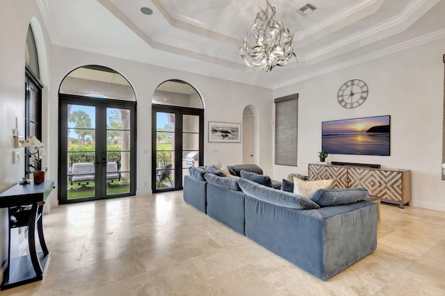 living room featuring a raised ceiling, ornamental molding, a notable chandelier, and french doors