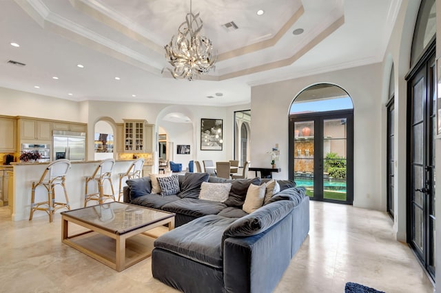 living room with french doors, crown molding, a notable chandelier, and a tray ceiling