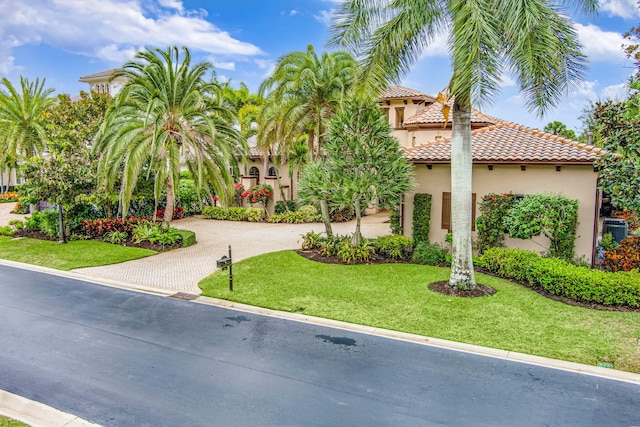 mediterranean / spanish-style home featuring central AC unit and a front yard